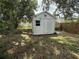 Backyard shed featuring weathered white siding with a window and a sliding door for storage at 2174 Schwalbe Way, Sarasota, FL 34235