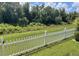 Scenic backyard view with lush greenery, a tranquil creek, and a charming white picket fence at 2244 Mauritania Rd, Punta Gorda, FL 33983