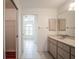 Bright bathroom featuring double sinks, vanity, a large mirror, and an open doorway to a bathtub at 23101 Hillsdale Ave, Port Charlotte, FL 33954