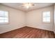 A cozy bedroom featuring hardwood floors, a ceiling fan, and two windows at 23101 Hillsdale Ave, Port Charlotte, FL 33954