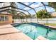 Beautiful screened-in pool area features a sparkling pool with surrounding brick patio at 2373 Chartwell Ave, North Port, FL 34288