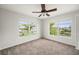 This comfy bedroom features plush carpeting, a ceiling fan, and multiple windows with natural light and a view of the neighborhood at 24261 Captain Kidd Blvd, Punta Gorda, FL 33955