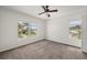 Bright bedroom with ceiling fan, carpeted floors, and views of tropical palm trees at 24261 Captain Kidd Blvd, Punta Gorda, FL 33955