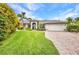 Charming single-story home with a manicured lawn, brick driveway, mature landscaping, and a two-car garage at 250 Freeport Ct, Punta Gorda, FL 33950