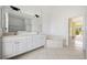 Bathroom featuring double sinks, a soaking tub, and tile flooring, with a doorway to the main bedroom at 264 Rotonda N Blvd, Rotonda West, FL 33947