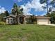 Inviting single-Gathering home with a two-car garage, lush green lawn, and beautiful palm trees in the front yard at 4823 Foxhall Rd, North Port, FL 34288