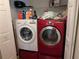 Well-organized laundry area with front loading white and red washer and dryer and storage shelving at 4823 Foxhall Rd, North Port, FL 34288
