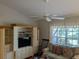 Living room featuring a white ceiling fan, and an entertainment center with drawers and a TV at 4823 Foxhall Rd, North Port, FL 34288