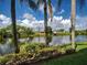 The backyard features lush landscaping, a beautiful lake, palm trees and cloud filled skies at 5725 Greenwood Ave # 5103, North Port, FL 34287