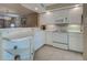 Well-lit kitchen with white cabinets and appliances, and a breakfast bar open to the living area at 5725 Greenwood Ave # 5103, North Port, FL 34287