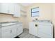 Well-lit laundry room with white cabinets, sink, shelving, and washer and dryer at 609 Monaco Dr, Punta Gorda, FL 33950