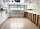Spacious garage with tile flooring and shelving, featuring a windowed garage door and room for storage and vehicles at 617 W Olympia Ave, Punta Gorda, FL 33950