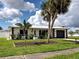 Charming single-story home with black and white accents, beautiful landscaping, and lush palm trees at 6483 Fabian Rd, North Port, FL 34287