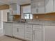 Bright kitchen featuring white cabinets, stainless steel hardware, granite countertops, and modern appliances at 6483 Fabian Rd, North Port, FL 34287