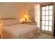 Bedroom with a pink bedspread, a small dresser, and a door leading to the outdoor area at 6689 Gasparilla Pines Blvd, Englewood, FL 34224