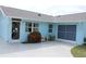 A blue home featuring a side entry door, small garden, and a two-car garage at 6689 Gasparilla Pines Blvd, Englewood, FL 34224