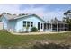 The back of the blue home features a screened in pool and landscaped gravel at 6689 Gasparilla Pines Blvd, Englewood, FL 34224