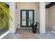 Elegant glass double-door entrance with stone landscaping, and columns creating an inviting first impression at 8081 Dimstead St, Port Charlotte, FL 33981