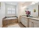 Elegant bathroom features a soaking tub with tile surround and a vanity with granite countertop at 1275 Blue Lake Cir, Punta Gorda, FL 33983
