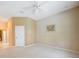 Spacious bedroom with neutral carpet, white ceiling fan, and access to hallway at 14311 Reserve Ct, Port Charlotte, FL 33953