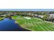 Scenic view of a golf course featuring lush greenery, a water hazard, and nearby residential homes at 14311 Reserve Ct, Port Charlotte, FL 33953