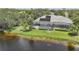 A screened-in pool and solar panels sit behind this Florida home on the edge of a lake surrounded by trees at 14311 Reserve Ct, Port Charlotte, FL 33953