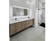 Modern bathroom featuring a double vanity with an illuminated mirror and a glass-enclosed shower at 14520 Edna Cir, Port Charlotte, FL 33981