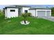 Well-manicured front yard featuring a young palm tree in a circular white rock bed with green grass at 14520 Edna Cir, Port Charlotte, FL 33981