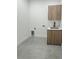 A modern laundry room features a sink, wooden cabinets, and gray tile flooring at 14520 Edna Cir, Port Charlotte, FL 33981