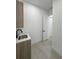 A sleek laundry room with gray tile features a sink, wooden cabinets, and white trim at 14520 Edna Cir, Port Charlotte, FL 33981