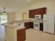 Well-lit kitchen featuring wood cabinetry, a breakfast bar, and white appliances at 15117 Lyneburg Ave, Port Charlotte, FL 33981