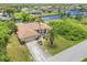Aerial view of the property with a canal view, a screened lanai, lush greenery, and a long driveway at 17125 Canary Ln, Port Charlotte, FL 33948