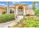 Welcoming front entrance with an arched doorway, decorative columns, secure gates, and manicured shrubbery at 17125 Canary Ln, Port Charlotte, FL 33948