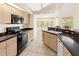 Kitchen featuring light wood cabinets, black countertops, and modern appliances and tile flooring at 17125 Canary Ln, Port Charlotte, FL 33948