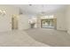 Open-concept living room with neutral walls, carpeting, and sliding doors leading to the outdoor pool area at 17125 Canary Ln, Port Charlotte, FL 33948