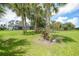 Lawn backyard with scattered mature palm trees and landscaping surrounding a screened-in pool and seating at 1722 Amnesty Dr, North Port, FL 34288