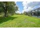 Sprawling lawn backyard with scattered mature trees and landscaping surrounding the screened-in pool at 1722 Amnesty Dr, North Port, FL 34288