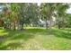 Beautiful lawn backyard with scattered mature palm trees and landscaping surrounding a screened-in pool at 1722 Amnesty Dr, North Port, FL 34288