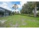 Beautiful lawn backyard with scattered mature trees and landscaping surrounding a screened-in pool at 1722 Amnesty Dr, North Port, FL 34288