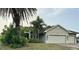 Charming single-story home featuring an attached two-car garage and lush landscaping with palm trees at 2143 Santonian Ter, North Port, FL 34286