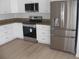 Modern kitchen featuring stainless steel appliances, white cabinets, granite countertops, and wood grain flooring at 23167 Turnbull Ave, Port Charlotte, FL 33954