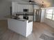 Bright kitchen features white cabinets, stainless steel appliances, and breakfast bar with granite countertops at 23167 Turnbull Ave, Port Charlotte, FL 33954