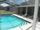 Inviting screened-in pool area with a clear blue pool, patio seating, and a relaxing lounge chair at 23167 Turnbull Ave, Port Charlotte, FL 33954