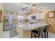 Well-lit kitchen with stainless steel appliances, an island with seating, and tiled backsplash with granite countertops at 25188 Marion Ave # 45, Punta Gorda, FL 33950