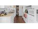 A narrow kitchen with white cabinets and appliances with wood style flooring and a view into the pantry at 3197 Normandy Dr, Port Charlotte, FL 33952