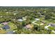 Overhead view of a residential area showcasing green yards, mature trees, and several homes with pools at 3305 Nansen Ln, North Port, FL 34286
