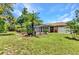 Lush backyard featuring a spacious lawn, mature trees, and a glimpse of the screened-in pool at 3305 Nansen Ln, North Port, FL 34286