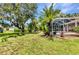 Picturesque backyard showcasing mature trees and a glimpse of the screened-in pool at 3305 Nansen Ln, North Port, FL 34286