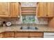 Kitchen sink with granite countertops, wooden cabinets and a window overlooking the backyard at 3305 Nansen Ln, North Port, FL 34286