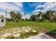 Large backyard with well-maintained lawn, palm trees, fenced perimeter, and stepping stones at 3497 Cohoes St, Port Charlotte, FL 33952